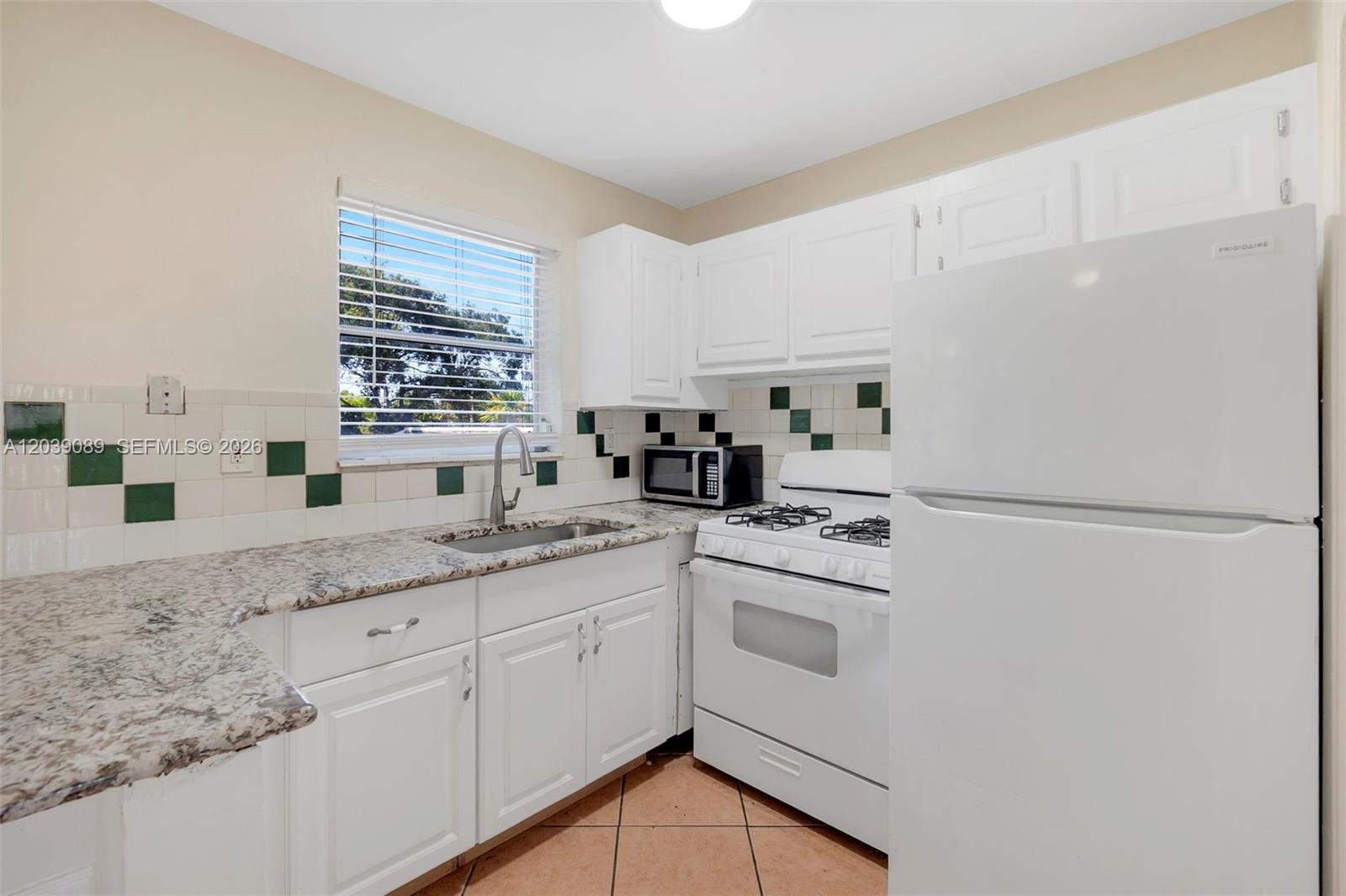 A kitchen features white cabinets, granite countertops, a gas stove, and a tiled backsplash — 2151 NW 64th Ave, Sunrise FL 33313, SUNRISE, FL