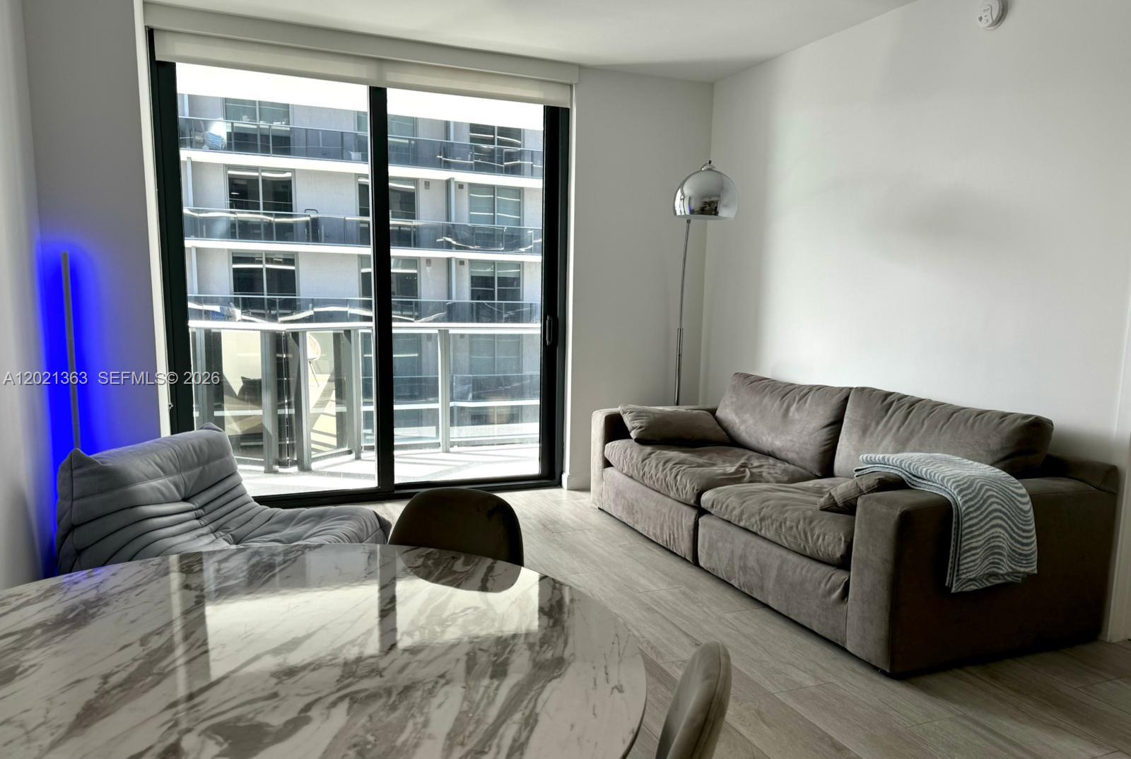 A living room features a grey sofa, a marble dining table, and a sliding glass door — 45 SW 9th St # 3107, Miami FL 33130, MIAMI, FL