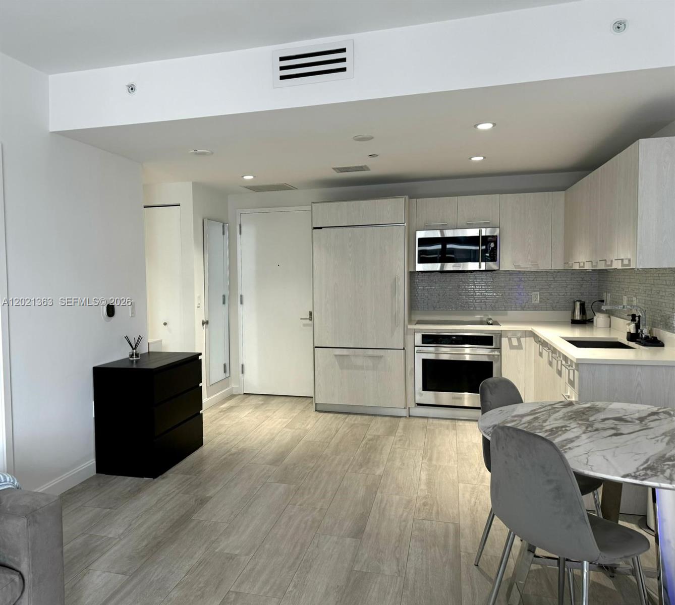 A modern kitchen features light wood cabinetry, stainless steel appliances, and a marble dining table — 45 SW 9th St # 3107, Miami FL 33130, MIAMI, FL