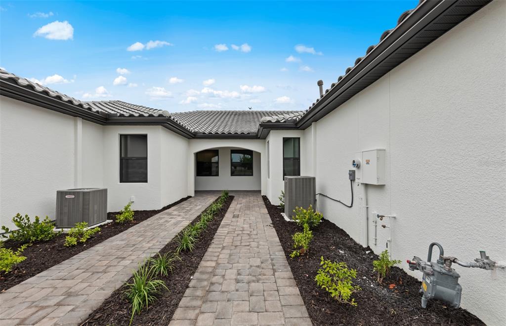 A paved walkway leads to a recessed entryway between two white stucco exterior walls — 14232 EAGLE BRANCH DRIVE, NOKOMIS, FL