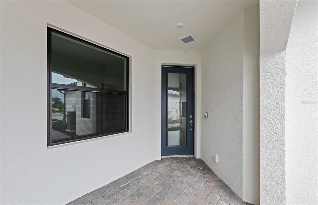 A covered entryway features a dark-framed glass door, a large window, and paver flooring — 14232 EAGLE BRANCH DRIVE, NOKOMIS, FL