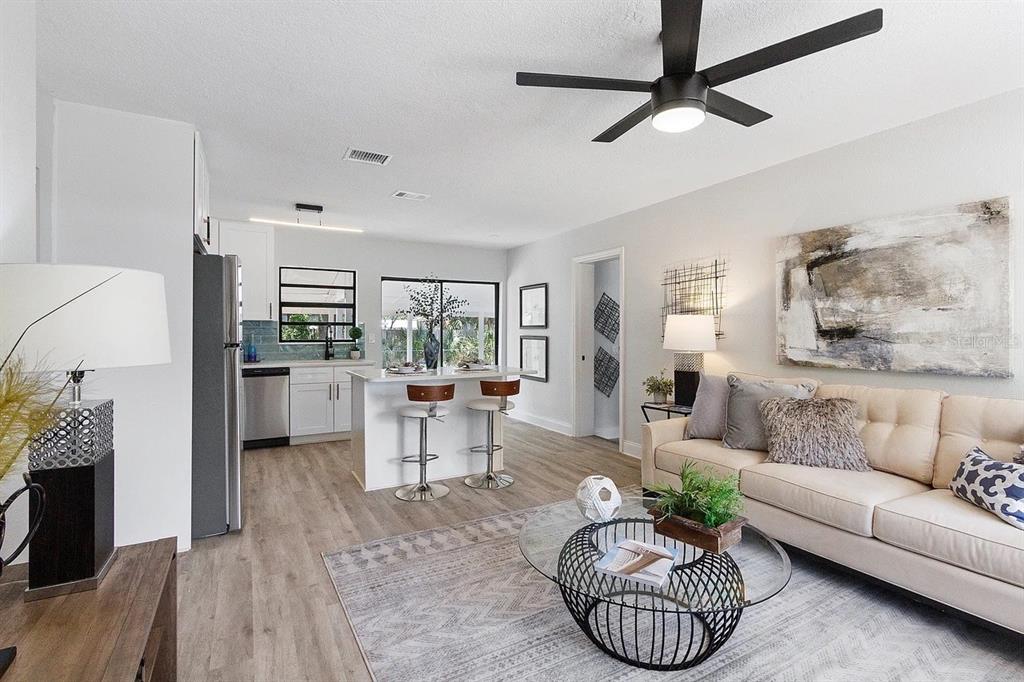 An open-concept living room and kitchen featuring light wood flooring and a ceiling fan — 4721 W WISCONSIN AVENUE, TAMPA, FL
