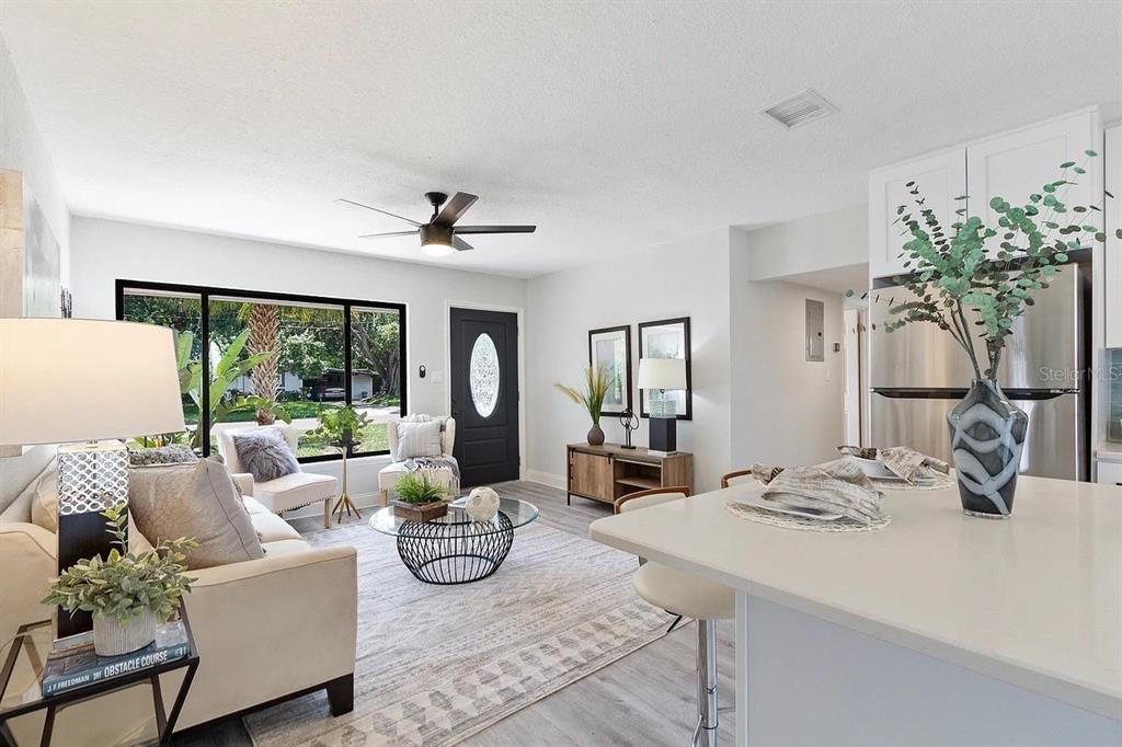 A bright living room with light flooring, a ceiling fan, and an open kitchen area — 4721 W WISCONSIN AVENUE, TAMPA, FL