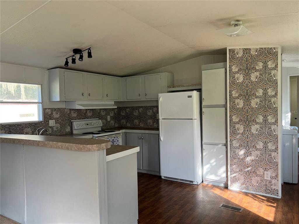 A kitchen features light gray cabinets, a white refrigerator, and patterned wallpaper on the walls — 835 MEMPHIS ROAD, LAKELAND, FL