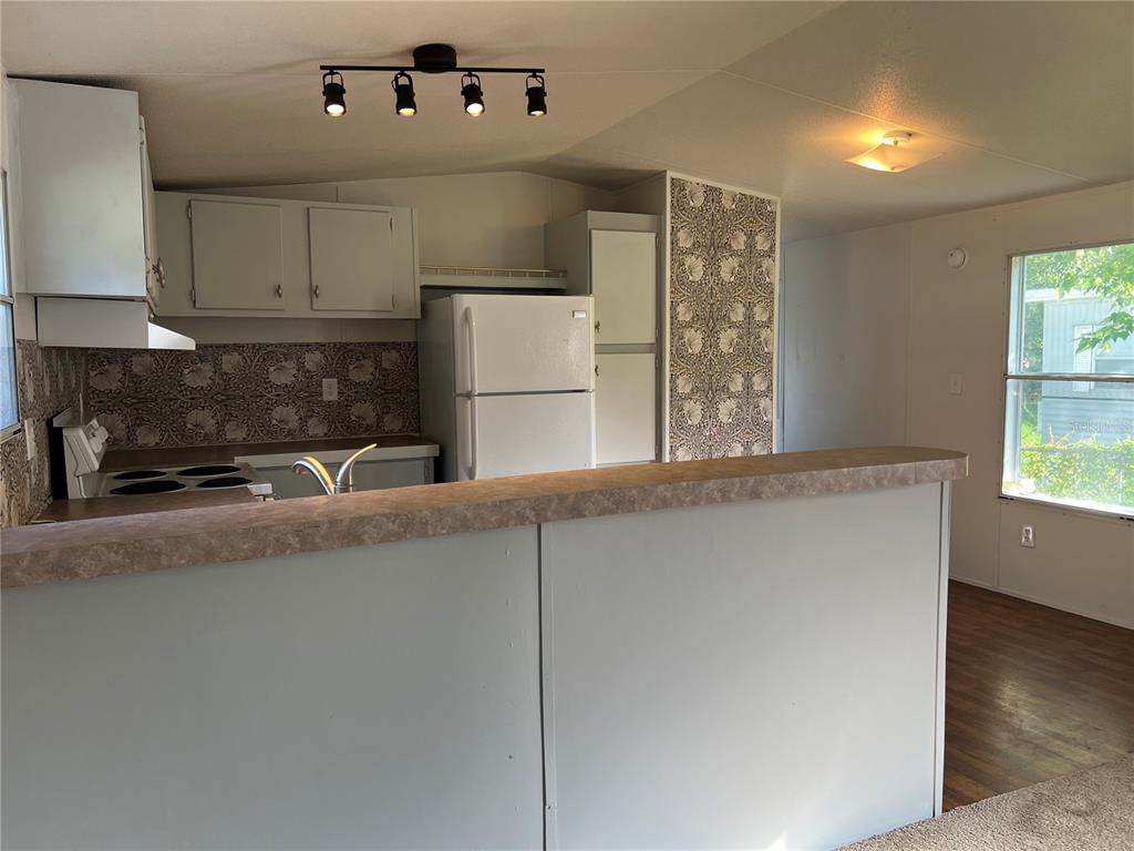 A kitchen with light-colored cabinets, patterned wallpaper, a white refrigerator, and a breakfast bar — 835 MEMPHIS ROAD, LAKELAND, FL