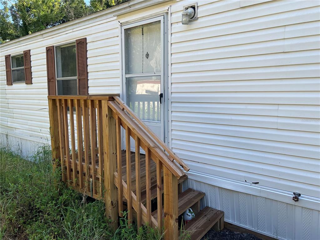 A wooden staircase with a railing leads to the front door of a mobile home — 835 MEMPHIS ROAD, LAKELAND, FL
