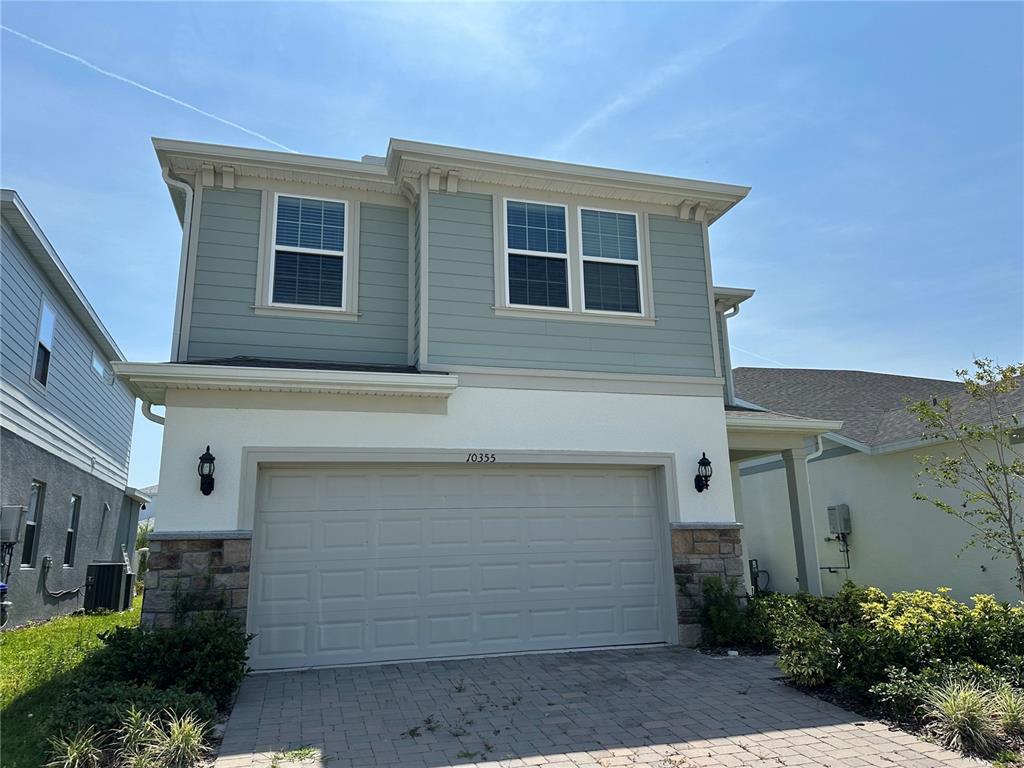 A two-story house features a light blue upper level, white stucco lower level, and garage — 10355 PARKVIEW RESERVE LANE, ORLANDO, FL
