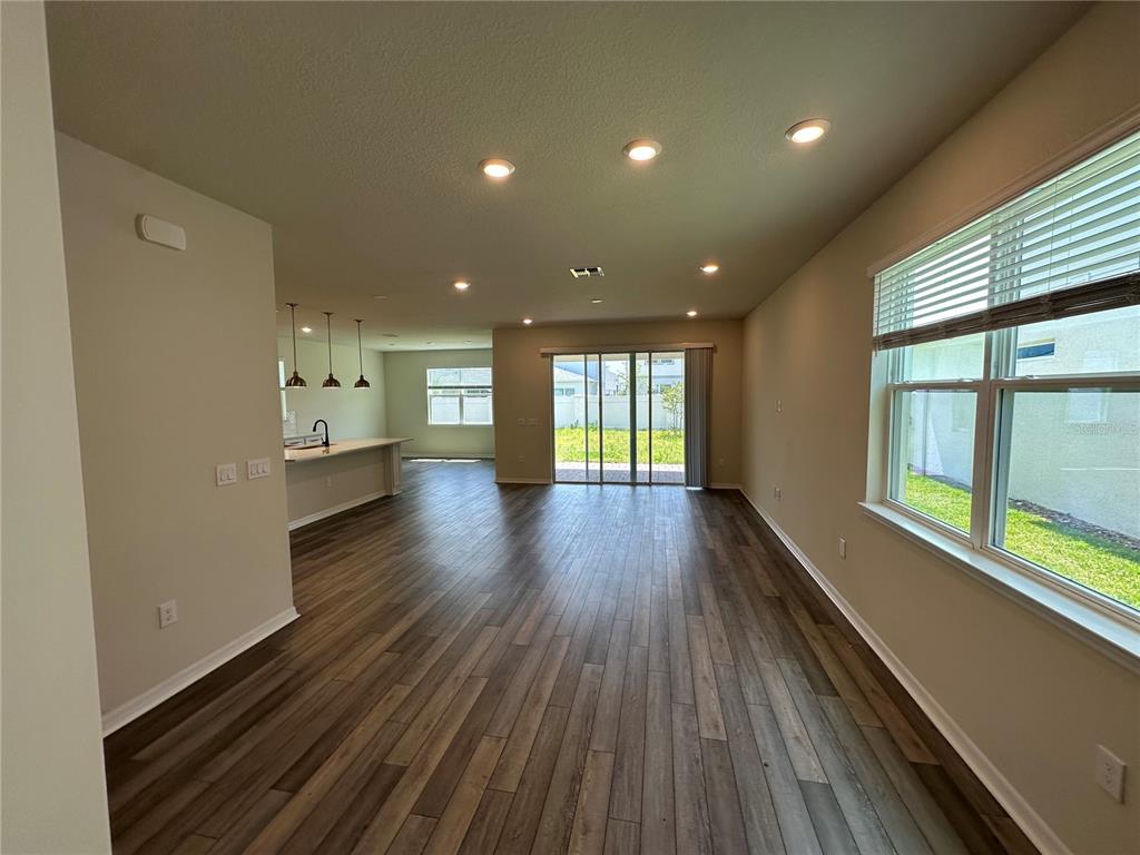 An open-concept living and kitchen area features wood-look flooring, recessed lighting, and sliding glass doors — 10355 PARKVIEW RESERVE LANE, ORLANDO, FL