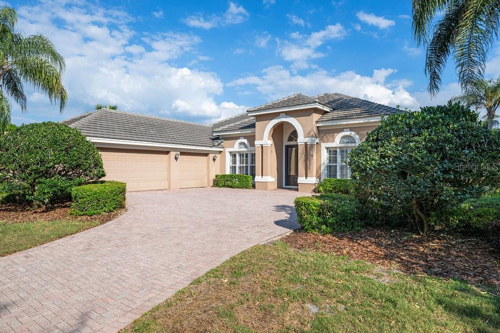The exterior of a house features a brick paver walkway leading to a double-door entrance — 2523 SAINT IGNATIUS COURT, ORLANDO, FL