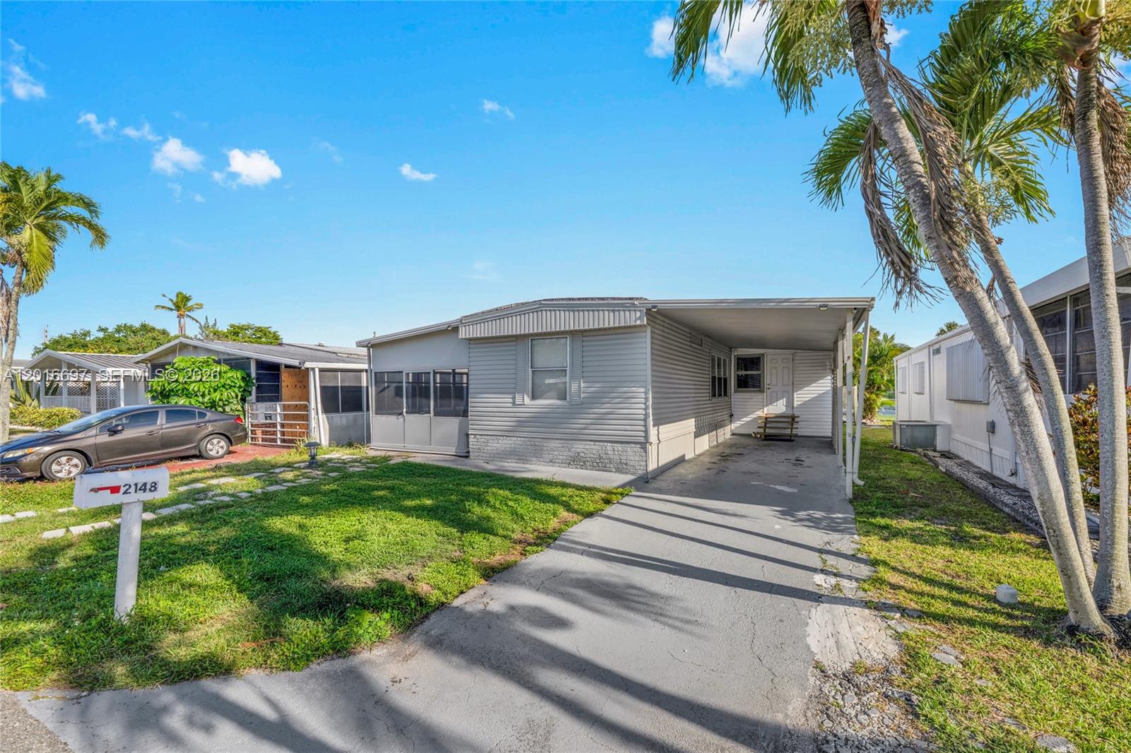 A living room features light wood flooring, a white media console, and a gray ceiling — 2148 SW 52nd St, Dania Beach FL 33312, DANIA BEACH, FL