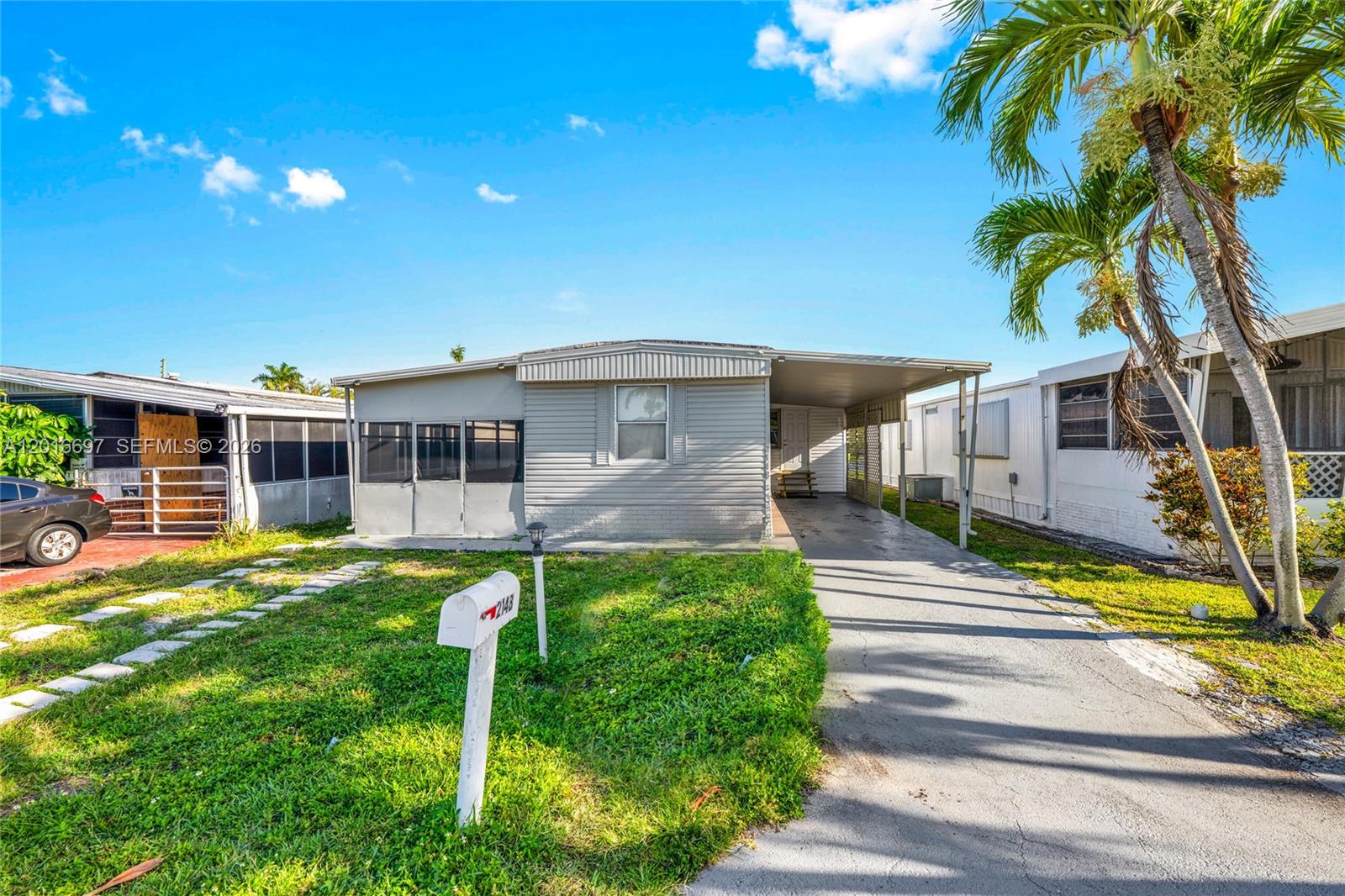 A living room features light wood-look flooring, a beige sofa, and a wall-mounted television — 2148 SW 52nd St, Dania Beach FL 33312, DANIA BEACH, FL