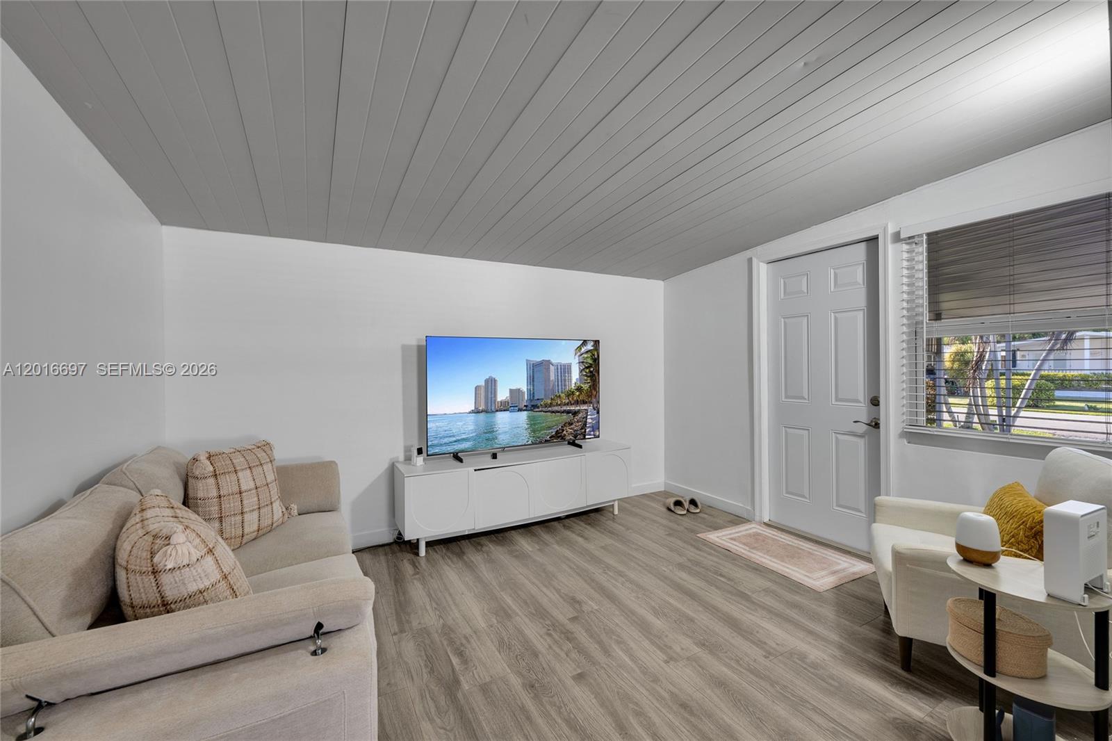 A living room features light wood-look flooring, white walls, a sofa, and a ceiling fan — 2148 SW 52nd St, Dania Beach FL 33312, DANIA BEACH, FL