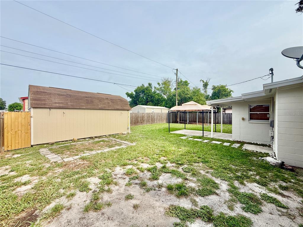 The backyard features a white house with a covered patio, a gazebo, and a wooden fence — 7810 FELICE AVENUE, TAMPA, FL
