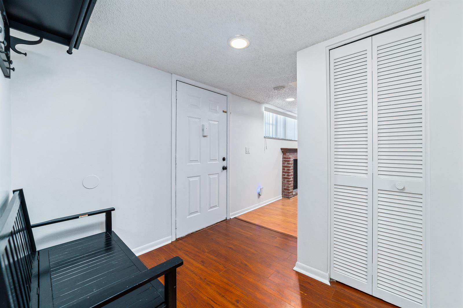 An entryway features wood-look flooring, a white front door, and a white louvered closet door — 8968 W Sample Road # 101, Coral Springs FL 33065, CORAL SPRINGS, FL