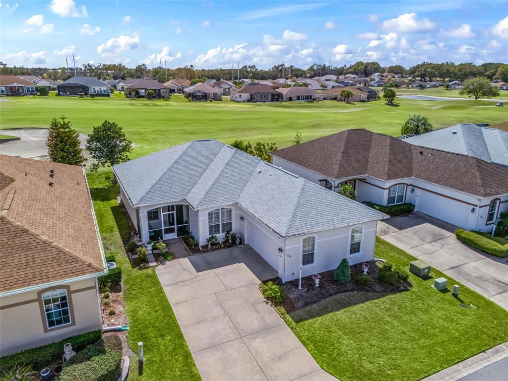 An aerial view of a single-story house with a driveway and a golf course backyard — 11900 SE 178TH STREET, SUMMERFIELD, FL