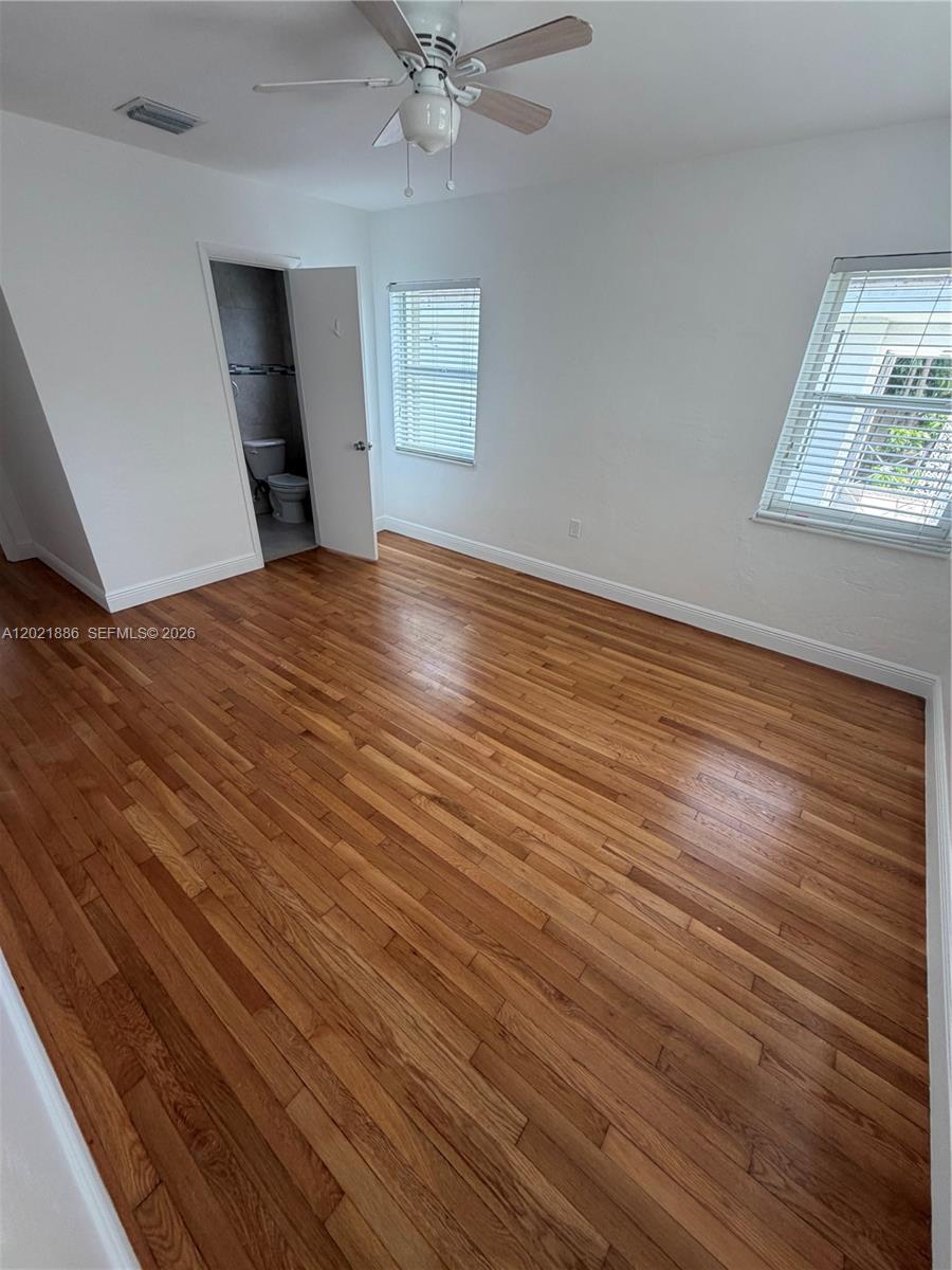 An empty bedroom features hardwood floors, white walls, a ceiling fan, and an attached bathroom — 3311 S Le Jeune Rd # 2, Coral Gables FL 33134, CORAL GABLES, FL
