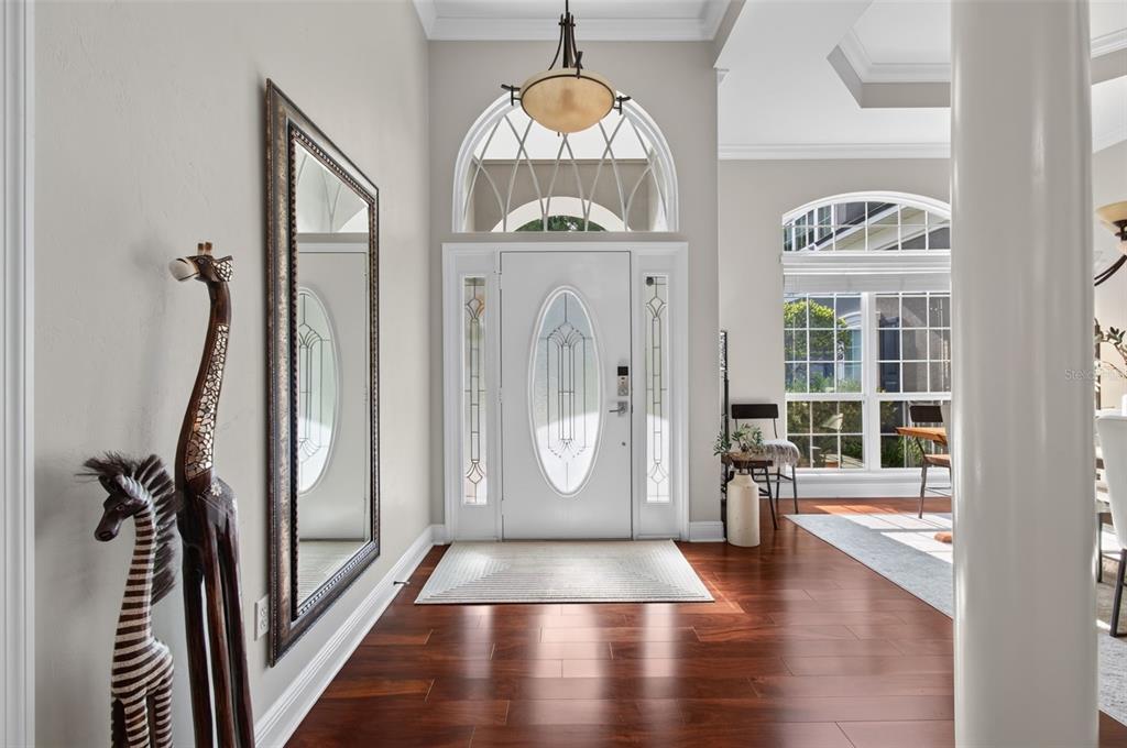A bright entryway features dark wood floors, a white front door, and a tall giraffe statue — 1326 SW 90TH STREET, GAINESVILLE, FL