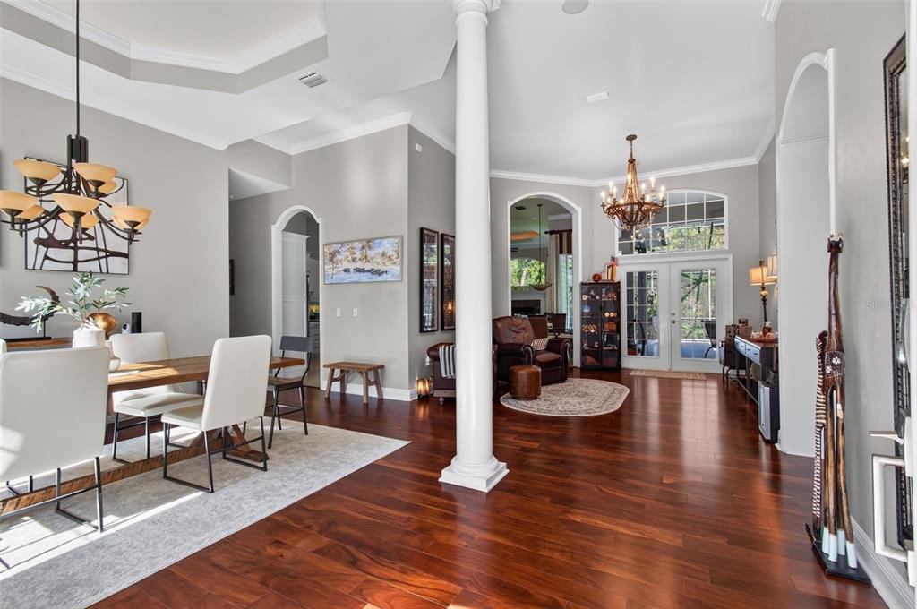 A dining area and living space feature hardwood floors, a white column, and chandeliers — 1326 SW 90TH STREET, GAINESVILLE, FL