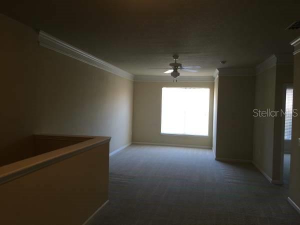 An interior view of a carpeted loft area with a ceiling fan and a window — 19914 VILLA CREEK DRIVE UNIT 203, ORLANDO, FL