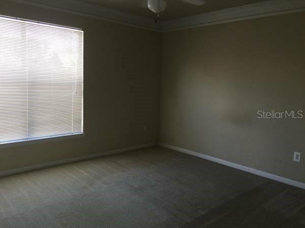 An empty bedroom features beige carpet, neutral walls, a ceiling fan, and a window with blinds — 19914 VILLA CREEK DRIVE UNIT 203, ORLANDO, FL