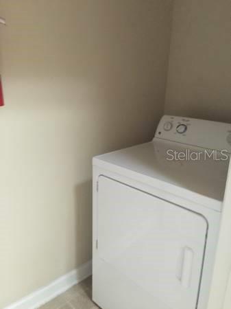 A white clothes dryer sits in a small laundry room with beige walls — 19914 VILLA CREEK DRIVE UNIT 203, ORLANDO, FL