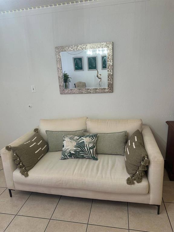 A cream-colored sofa with decorative pillows sits against a wall beneath a framed mirror — 43420 HIGHWAY 27 UNIT 445, DAVENPORT, FL