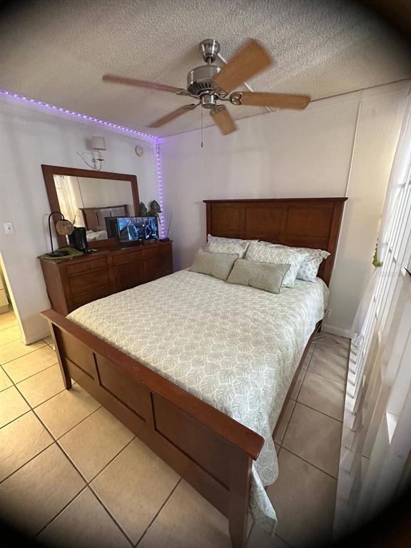 A bedroom features a wooden bed frame, a matching dresser with a mirror, and tile flooring — 43420 HIGHWAY 27 UNIT 445, DAVENPORT, FL