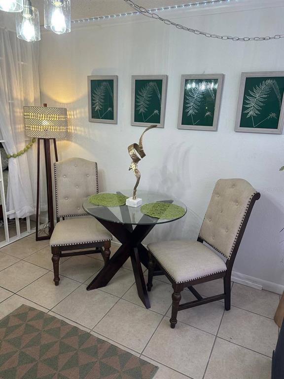 A small dining area features a glass-topped table, two upholstered chairs, and four framed prints — 43420 HIGHWAY 27 UNIT 445, DAVENPORT, FL