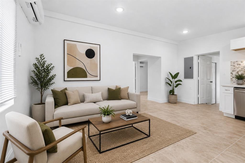 A bright living room features a beige sofa, wooden coffee table, and light tile flooring — 918 FERNDELL ROAD, ORLANDO, FL