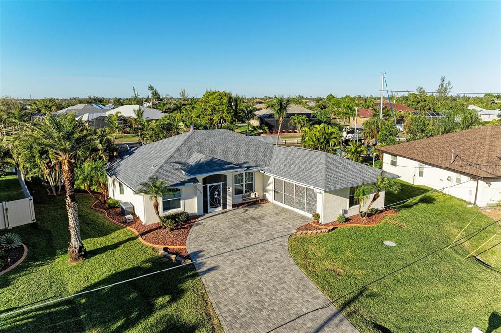 An aerial view of a single-story house with a gray shingled roof and paver driveway — 14968 LYNEBURG AVENUE, PORT CHARLOTTE, FL