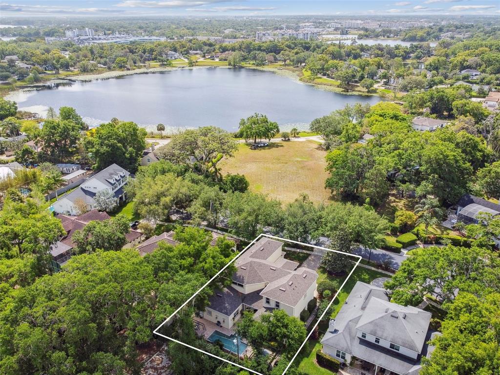 An aerial view shows a house with a pool, surrounded by trees near a lake — 755 CRANES COURT, MAITLAND, FL