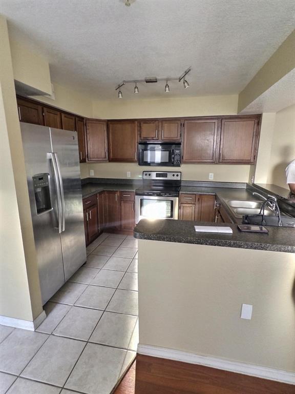 A kitchen features dark wood cabinets, stainless steel appliances, and a tiled floor — 13803 FAIRWAY ISLAND DRIVE UNIT 1618, ORLANDO, FL
