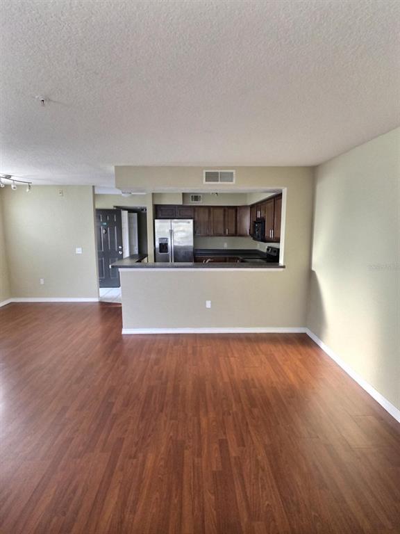 A view of a living area with wood-look flooring looking toward an open kitchen — 13803 FAIRWAY ISLAND DRIVE UNIT 1618, ORLANDO, FL