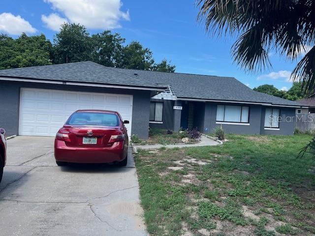 A red sedan is parked in the driveway of a single-story house with gray siding — 6280 MISSON DRIVE, ORLANDO, FL