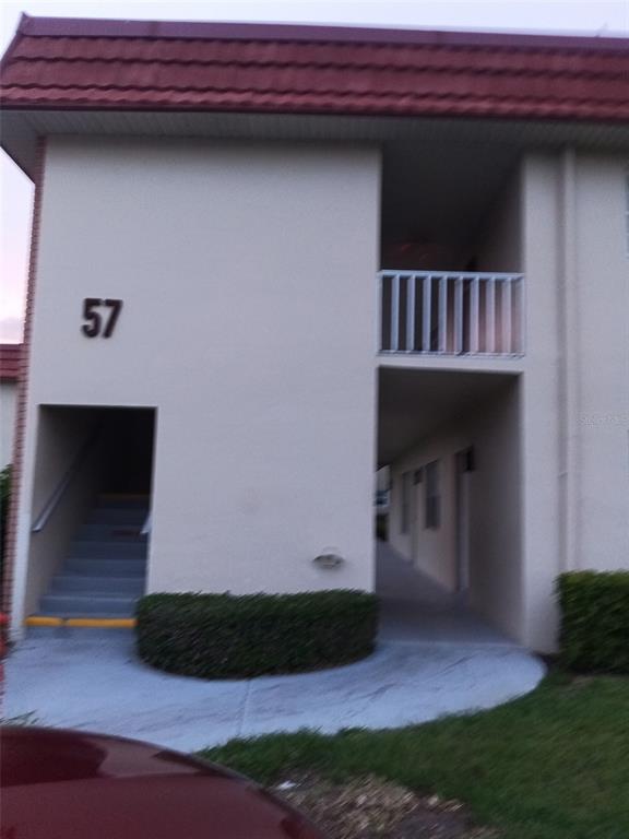 An exterior view of a two-story apartment building with a staircase and a balcony — 57 WOODLAND DRIVE UNIT 102, VERO BEACH, FL