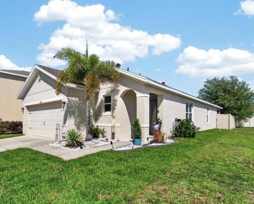 A single-story house with a beige stucco exterior, a two-car garage, and a palm tree — 16829 TRITE BEND STREET, WIMAUMA, FL