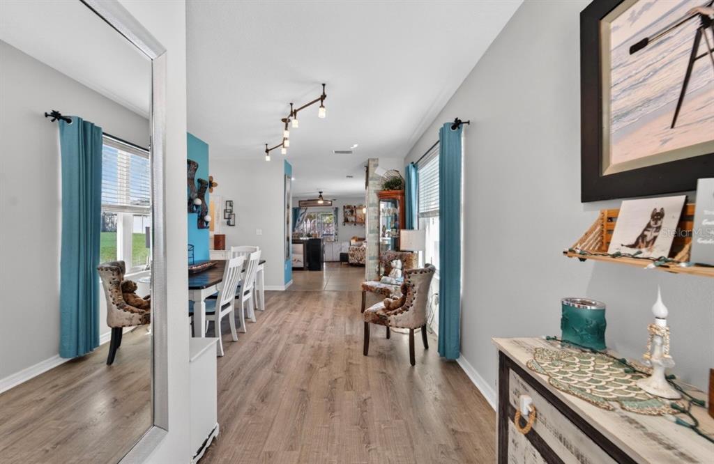 A dining area with wood-look flooring leads to an open-concept kitchen and living space — 16829 TRITE BEND STREET, WIMAUMA, FL