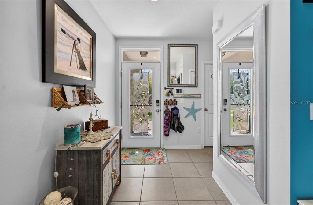 An entryway features tile flooring, a decorative front door, a large mirror, and a console table — 16829 TRITE BEND STREET, WIMAUMA, FL