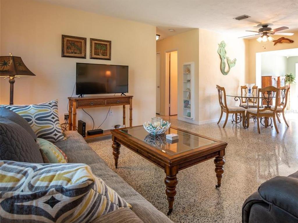 A living room with a sofa, coffee table, television, and an adjacent dining area — 2456 ELKCAM BOULEVARD, PORT CHARLOTTE, FL