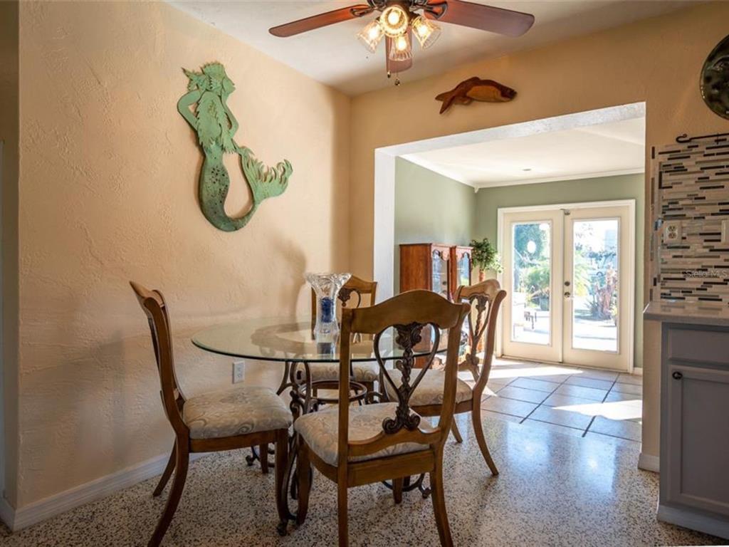 A dining area features a glass-topped table, four wooden chairs, and a mermaid wall decoration — 2456 ELKCAM BOULEVARD, PORT CHARLOTTE, FL