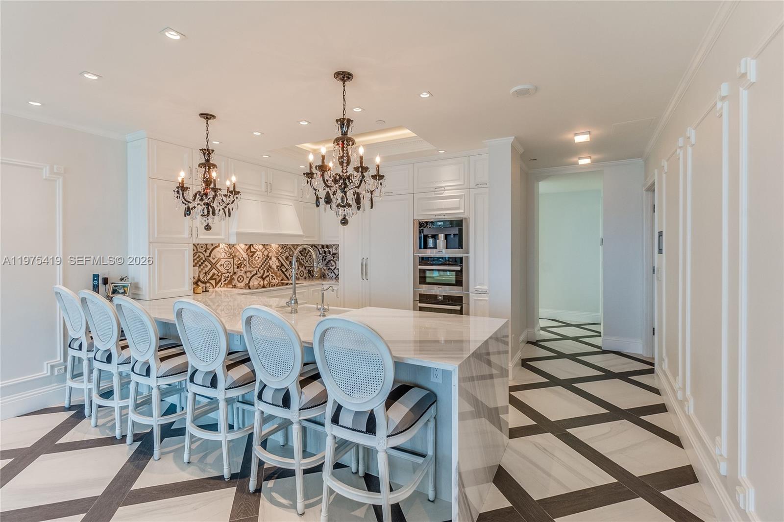 A white kitchen features a marble-topped island, crystal chandeliers, and a patterned tile floor — 1455 Ocean Dr # 1607, Miami Beach FL 33139, MIAMI BEACH, FL
