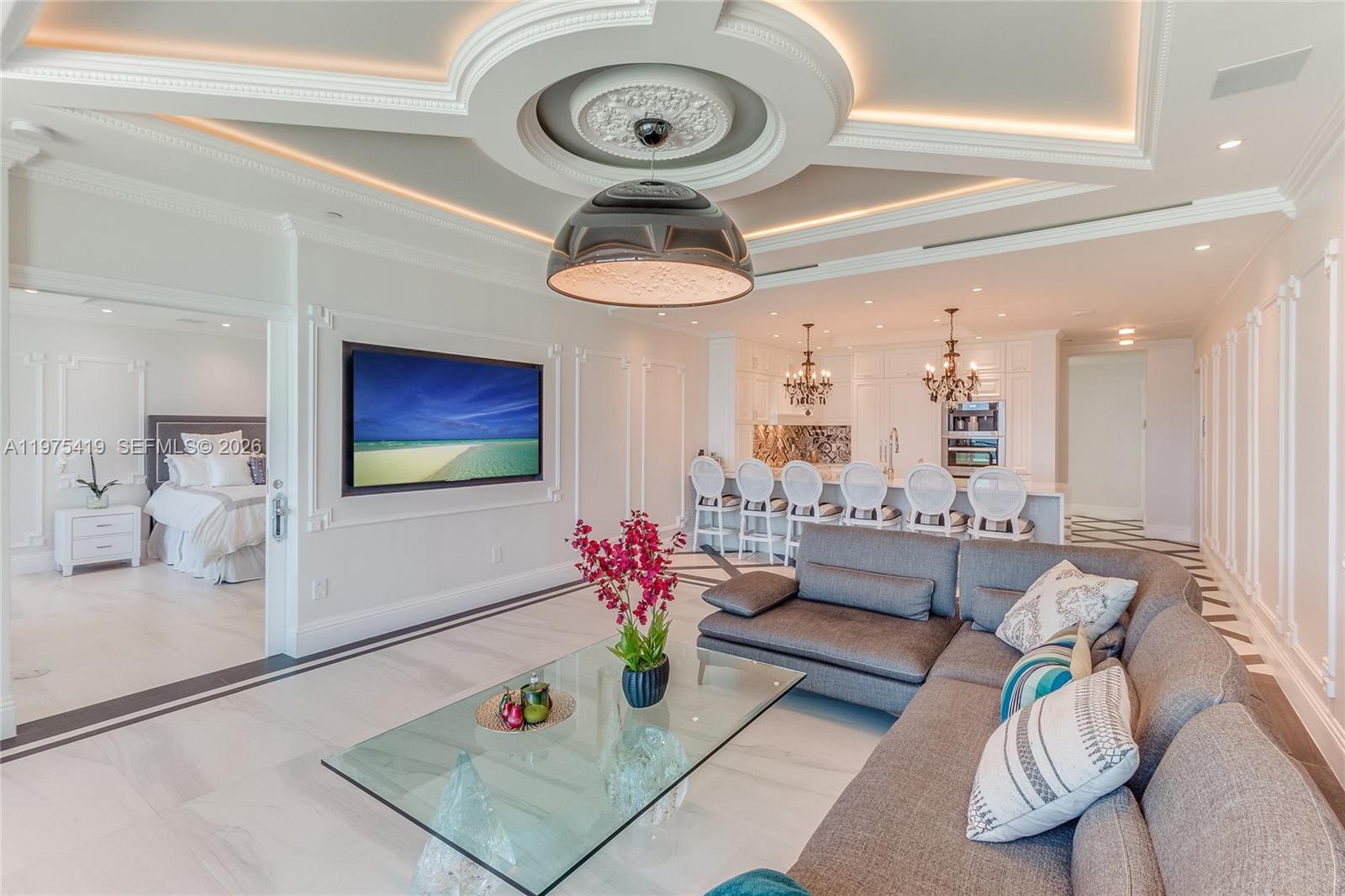 A modern living room with a gray sectional, glass coffee table, and open kitchen area — 1455 Ocean Dr # 1607, Miami Beach FL 33139, MIAMI BEACH, FL