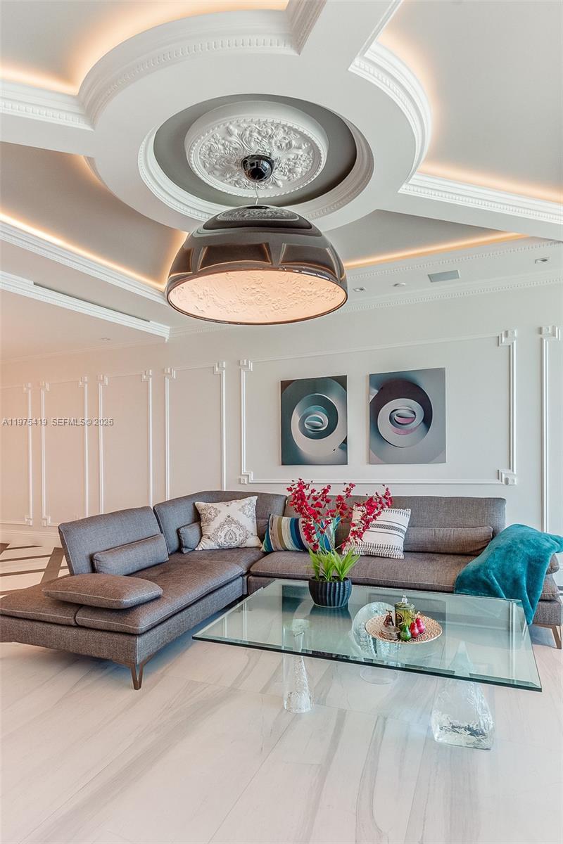 A modern living room features a gray sectional sofa, glass coffee table, and ornate ceiling molding — 1455 Ocean Dr # 1607, Miami Beach FL 33139, MIAMI BEACH, FL