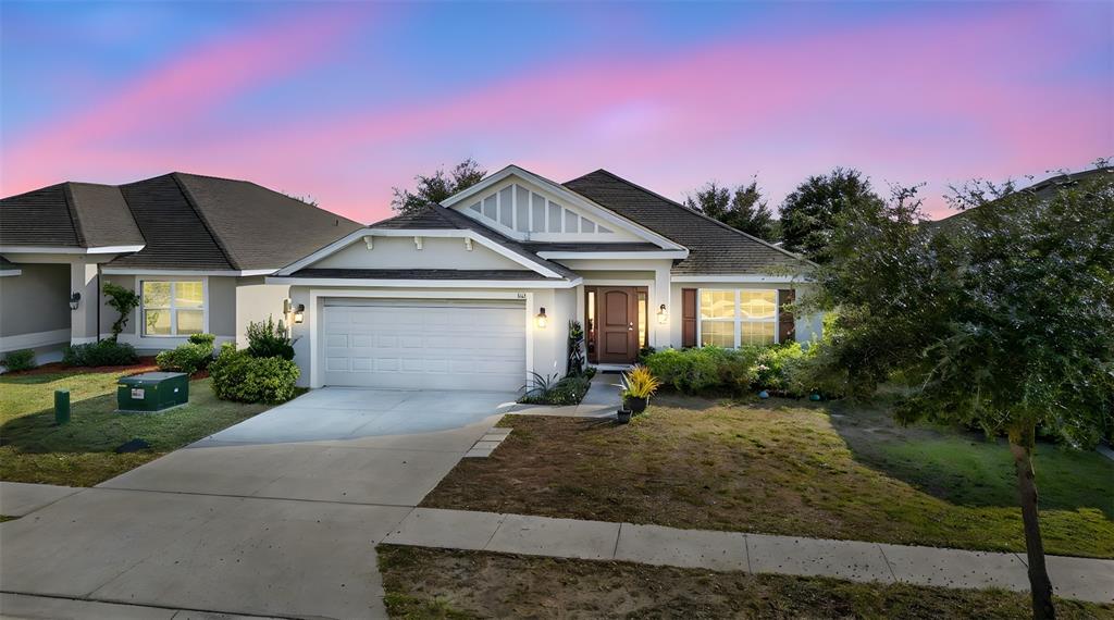 A single-story suburban house with a two-car garage and a front yard at sunset — 383 BUCHANNAN DRIVE, DAVENPORT, FL