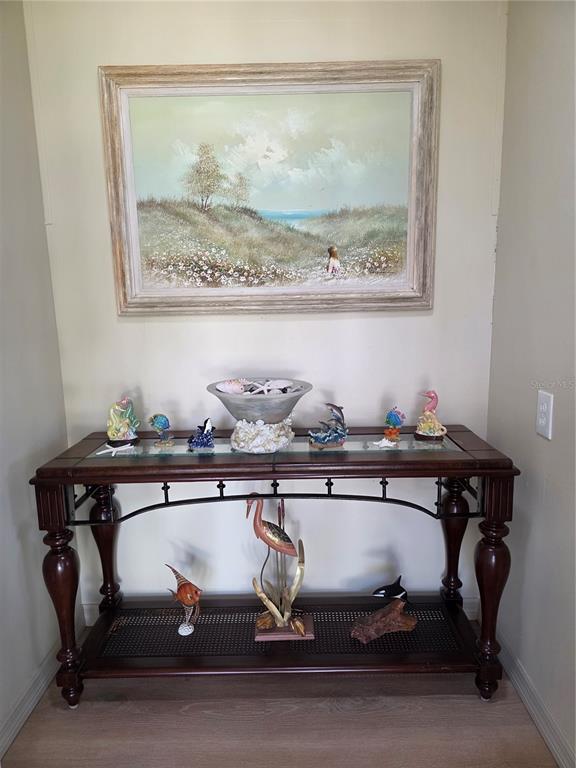 A wooden console table with nautical decor sits beneath a landscape painting in an entryway — 6228 FALCON DRIVE, ENGLEWOOD, FL