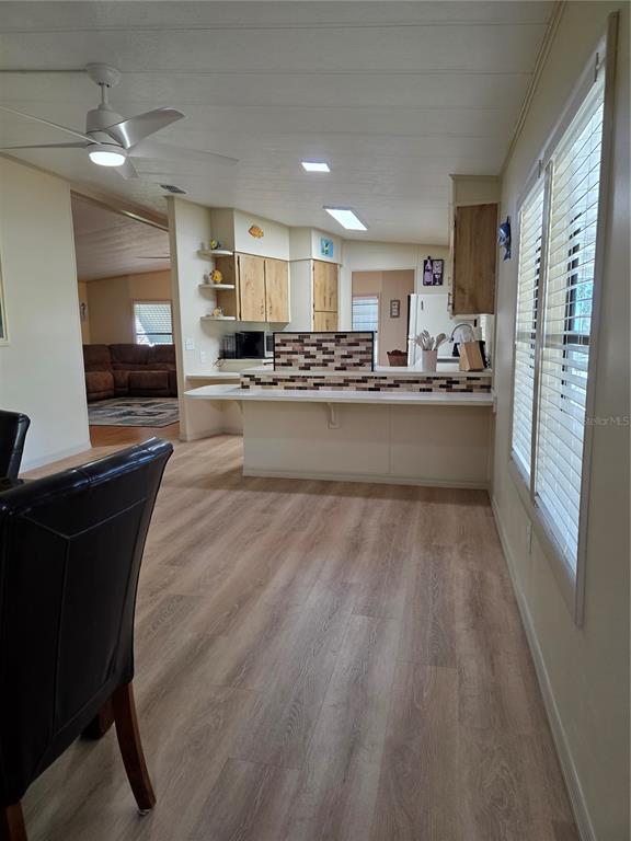 A kitchen with a breakfast bar, light wood cabinets, and wood-look flooring — 6228 FALCON DRIVE, ENGLEWOOD, FL