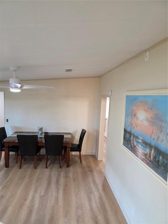 A dining area features a dark wood table, four black chairs, and a coastal painting — 6228 FALCON DRIVE, ENGLEWOOD, FL
