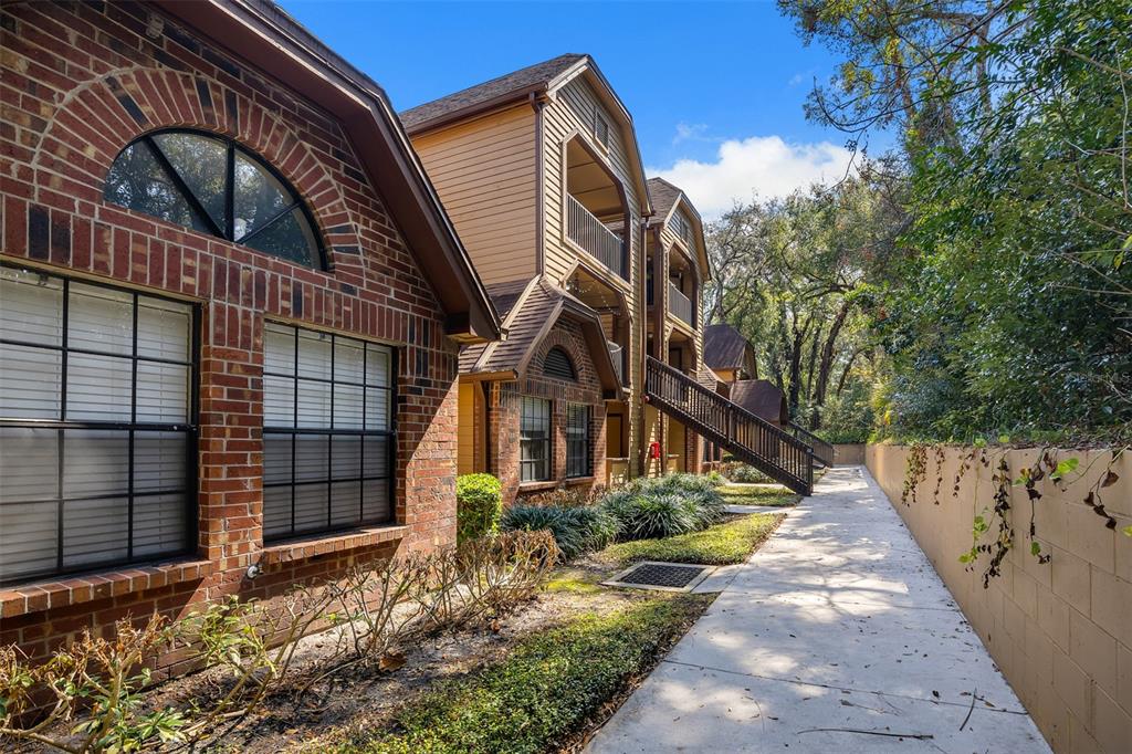 A brick and tan siding apartment building exterior with a sidewalk and wooden staircase — 485 FORESTWAY CIRCLE UNIT 106, ALTAMONTE SPRINGS, FL