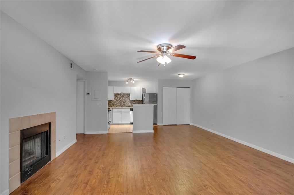 A living room with wood-look flooring, a fireplace, and an open view into the kitchen — 485 FORESTWAY CIRCLE UNIT 106, ALTAMONTE SPRINGS, FL