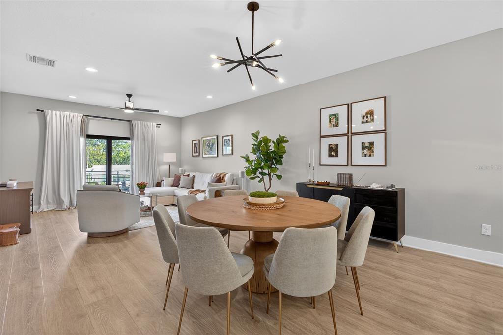 A dining area with a round wooden table and chairs sits before a living room — 2526 13TH AVENUE N, ST PETERSBURG, FL
